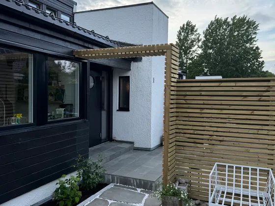 Levegg i tre ved uteplass med skifer og hvit singel i fugene