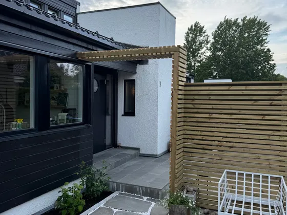 Levegg i tre ved uteplass med skifer og hvit singel i fugene