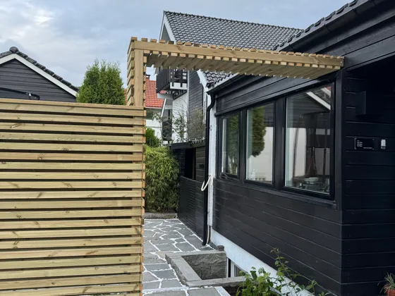 Inngangsparti med bruddskifer, granittkant og levegg i lakkert tre