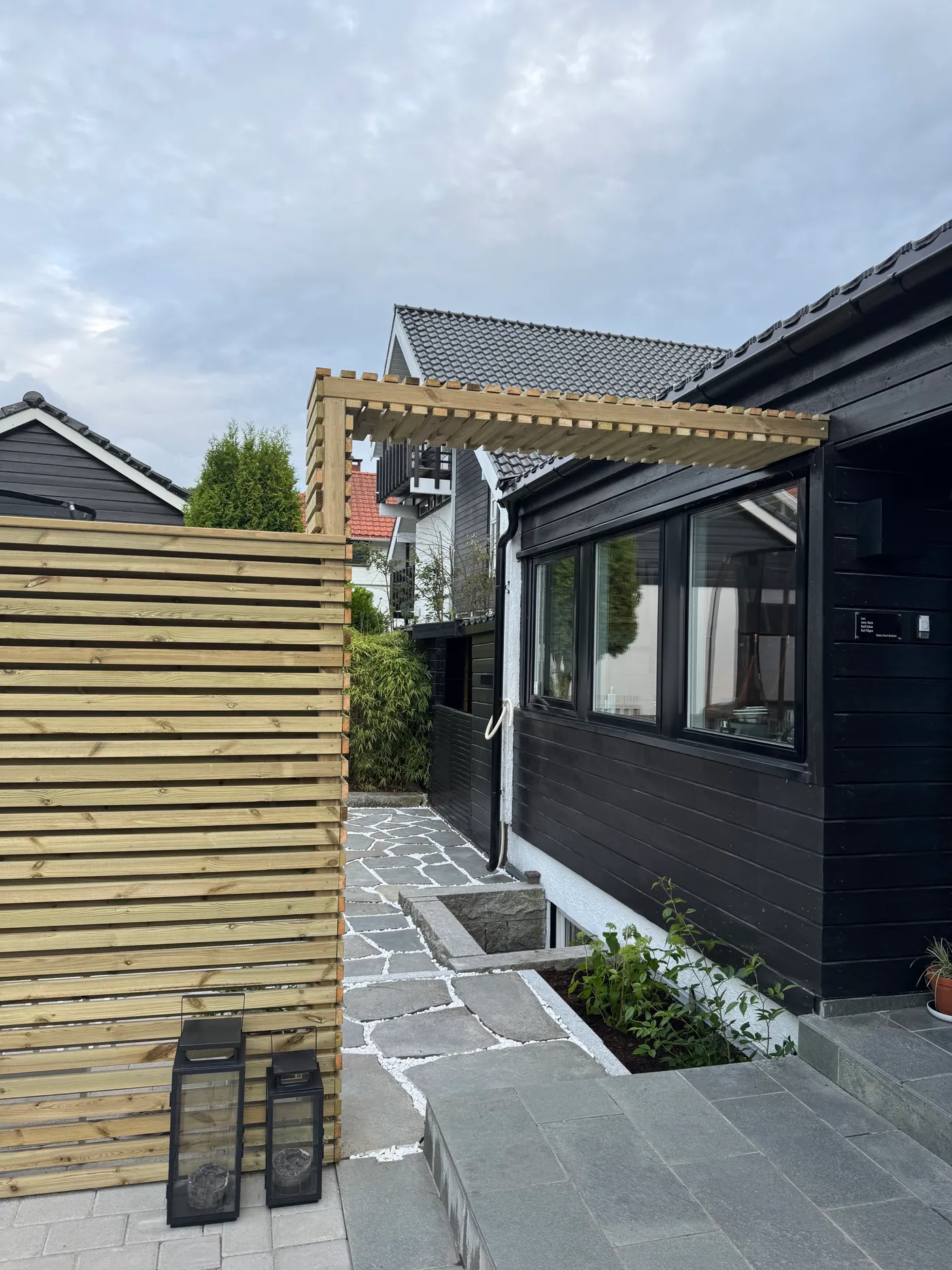 Inngangsparti med bruddskifer, granittkant og levegg i lakkert tre