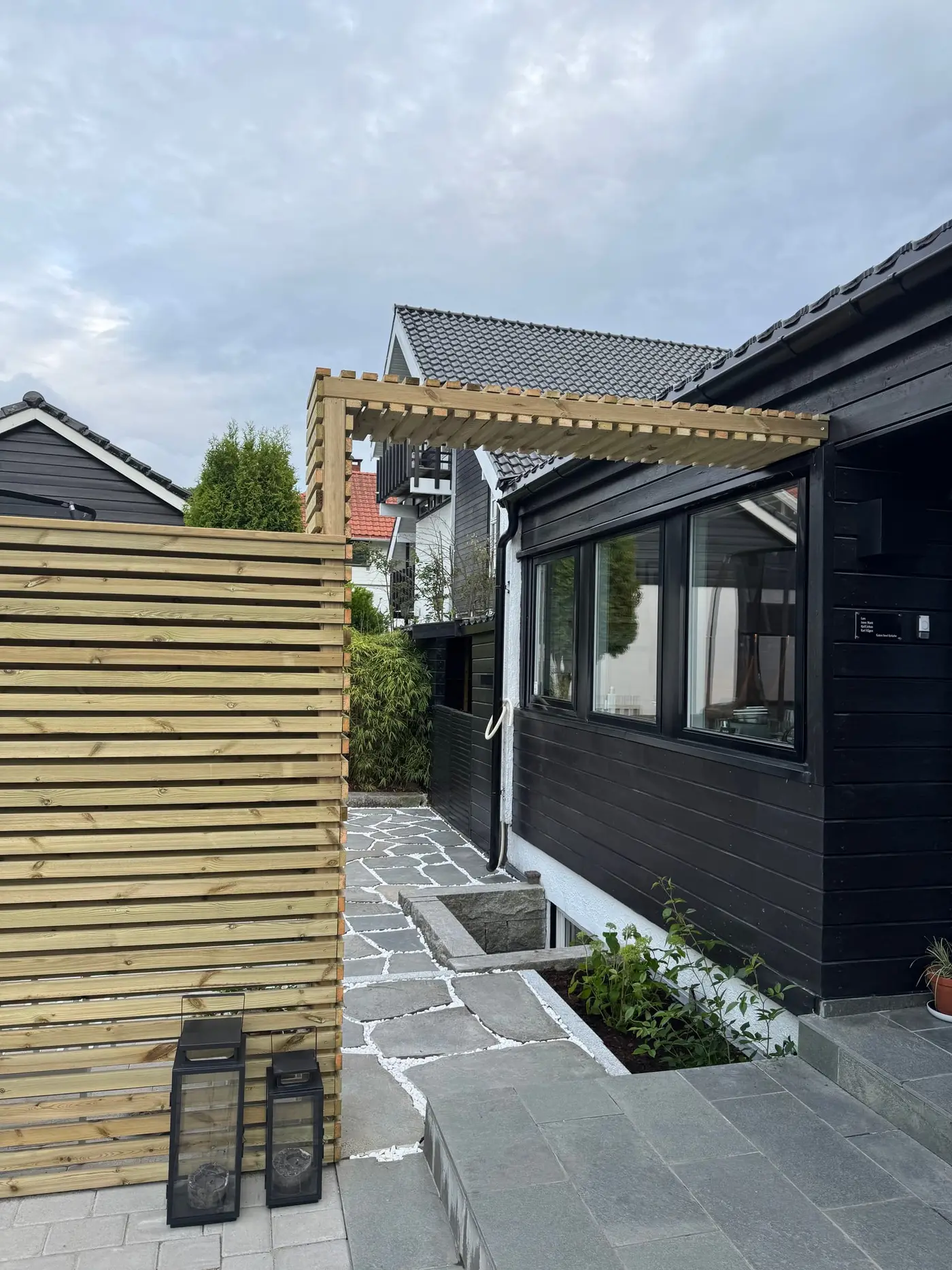 Inngangsparti med bruddskifer, granittkant og levegg i lakkert tre