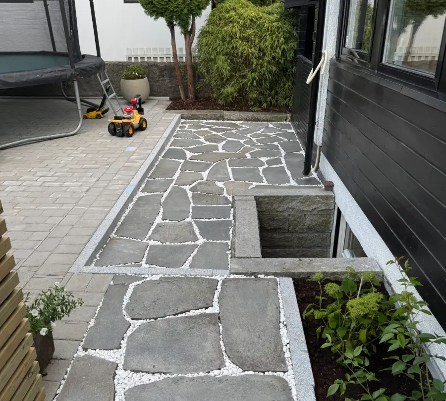 Bruddskifer med hvit singel i fugene, granittkantstein og belegningsstein ved husvegg