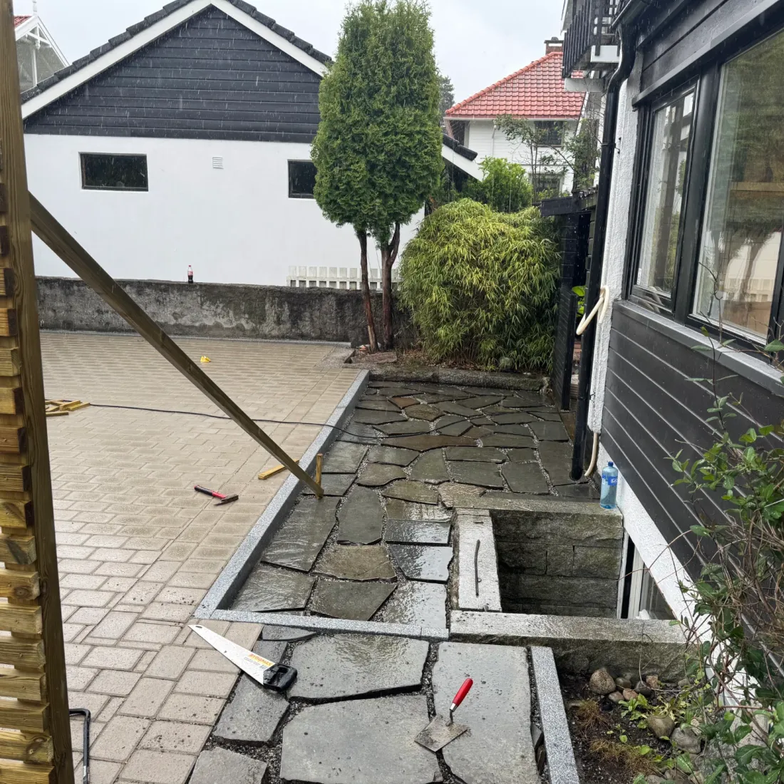 Bruddskifer legges langs husveggen, granittkant mot belegningsstein og lysgrav