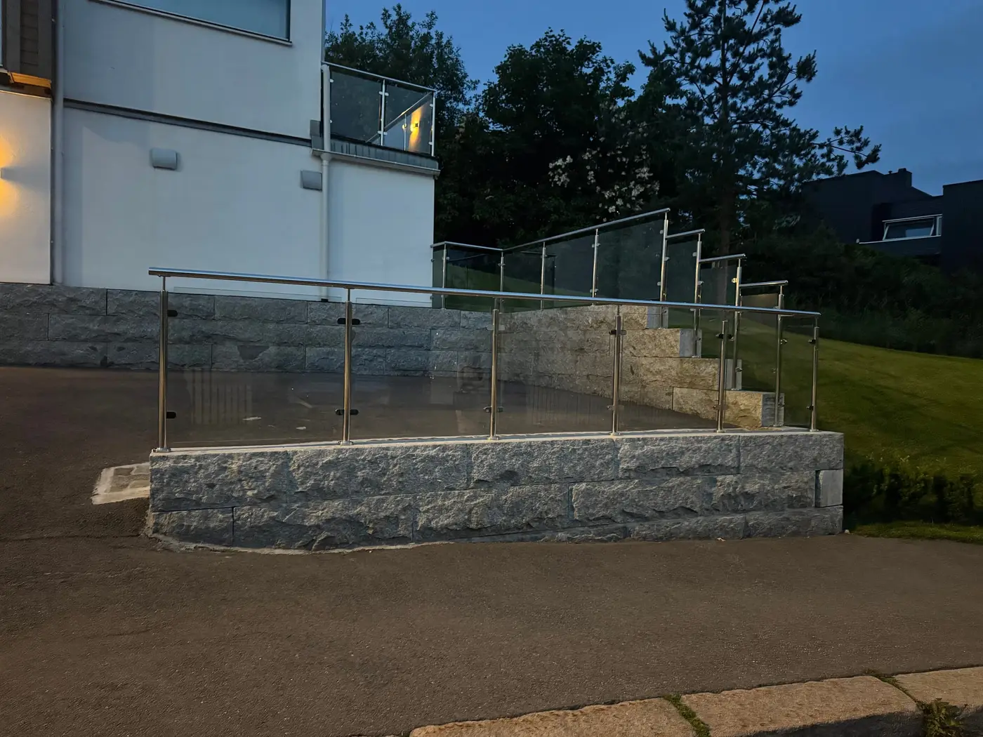 Granittmur med glassrekkverk i kveldslys