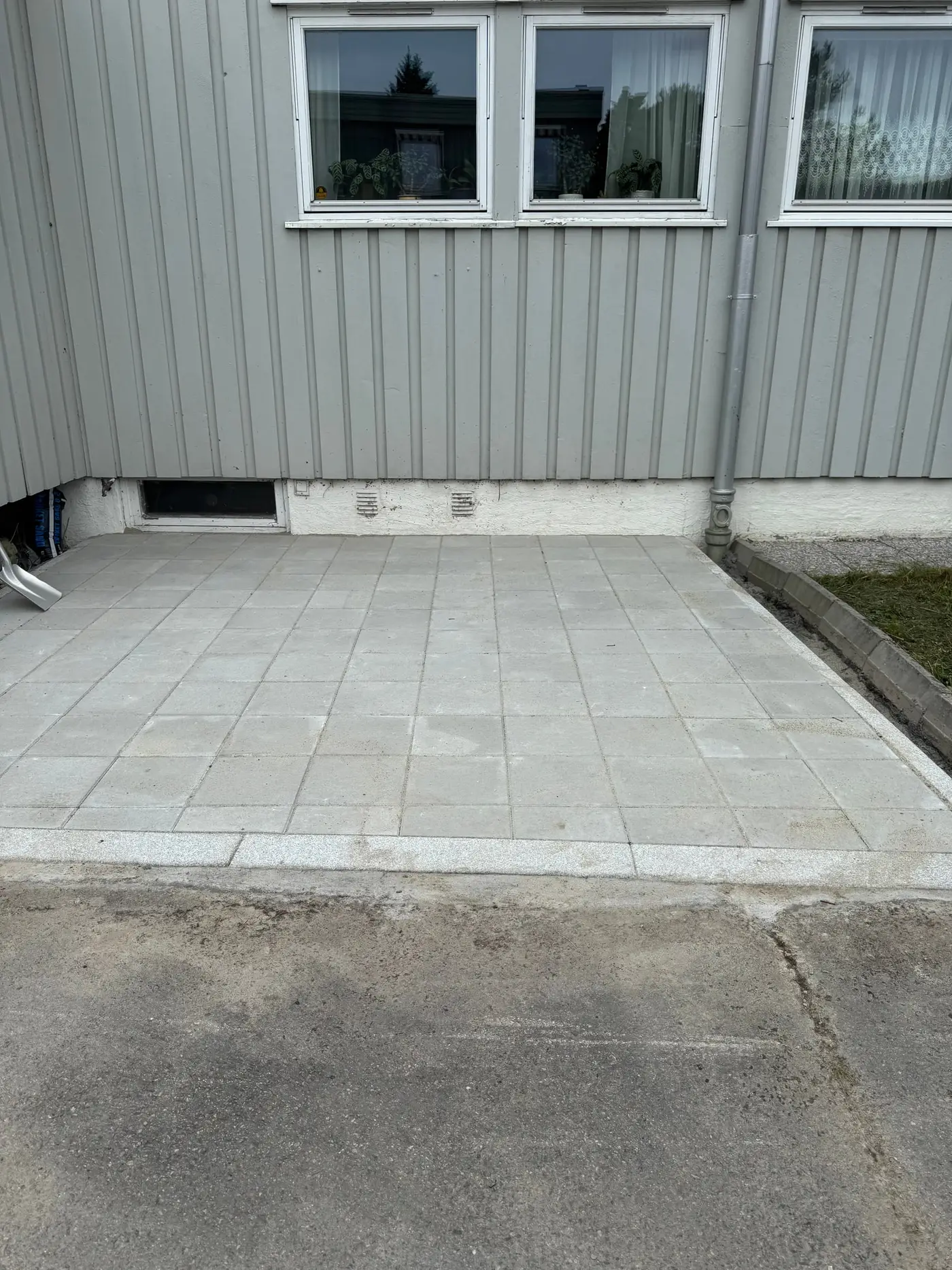 Liten uteplass i lyse betongheller med granittkant mot asfalt