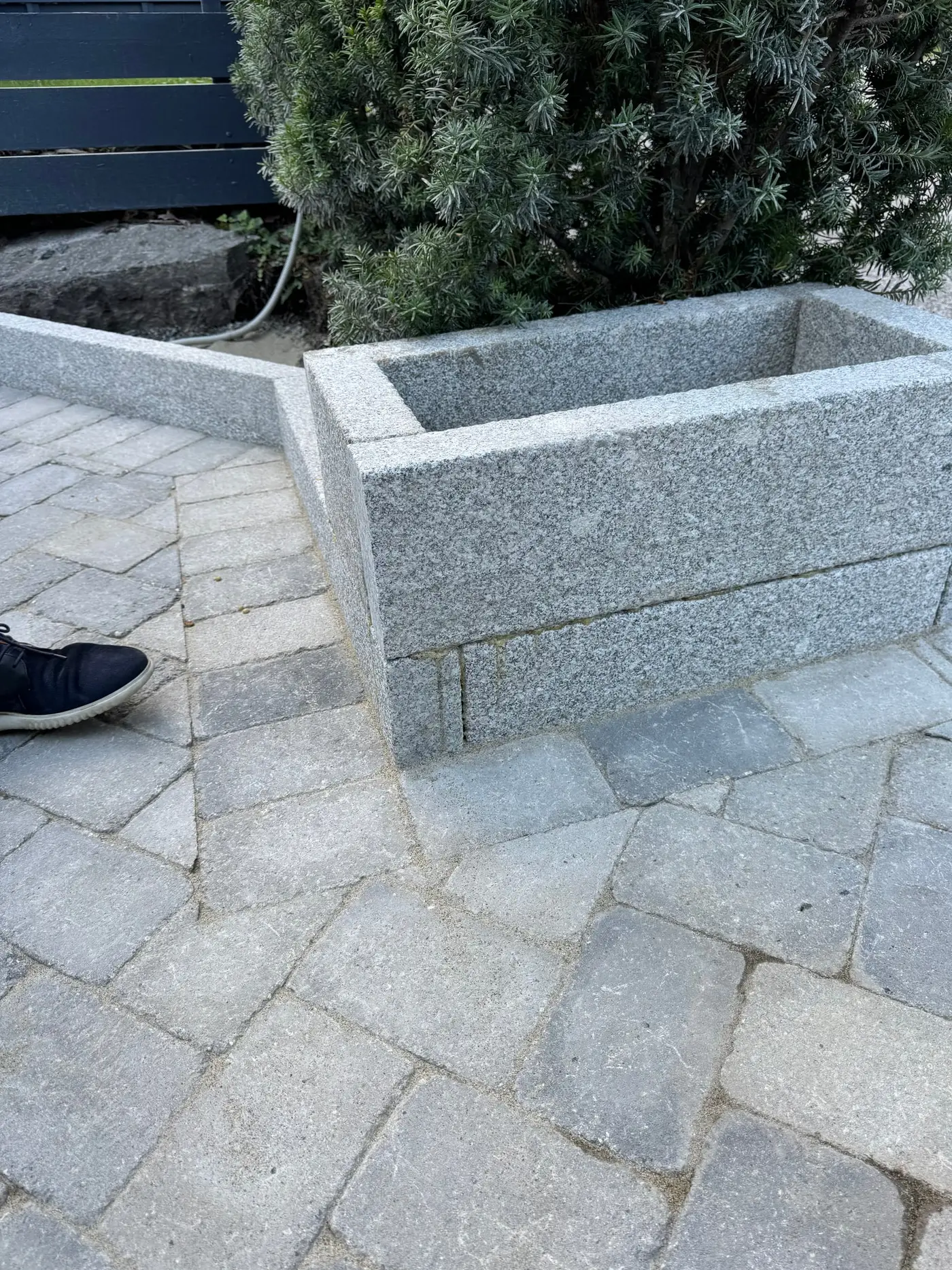 Plantekasse og lav kant i sagde granittblokker inntil steinlagt gårdsplass