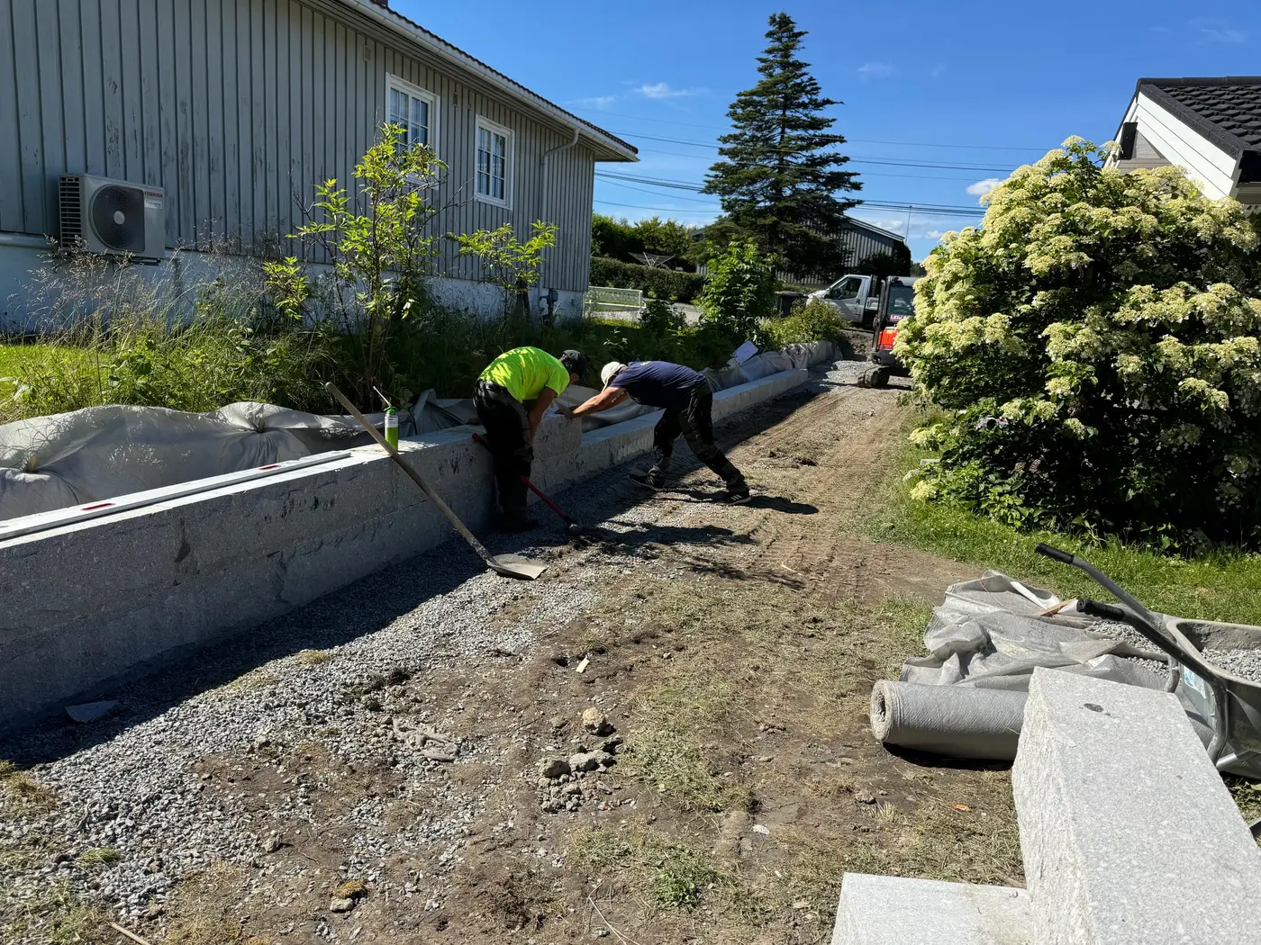 To av våre folk bygger lav mur av store steinblokker langs hus