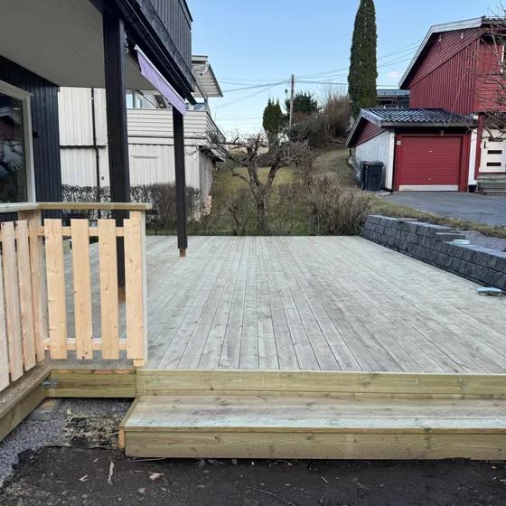 Lav platting i impregnert tre med trinn og betongstøttemur