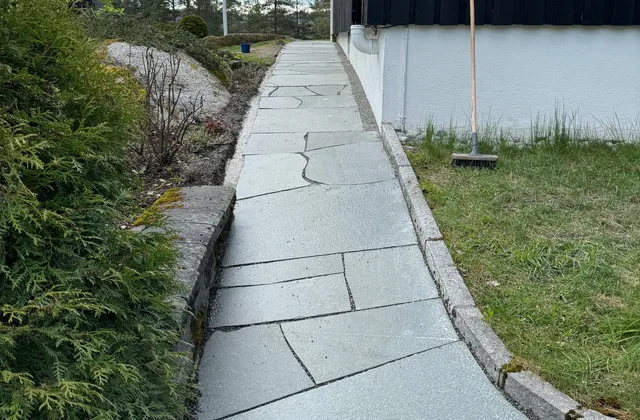 Gangvei i lys naturskifer langs husvegg med granitt kantstein