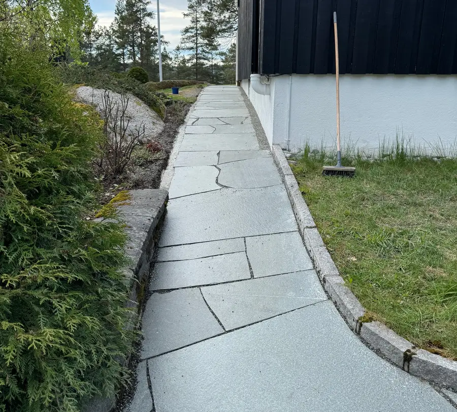 Gangvei i lys naturskifer langs husvegg med granitt kantstein