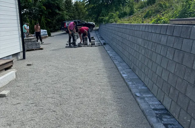 Lang støttemur i grå betongblokk langs oppkjørsel under opparbeiding