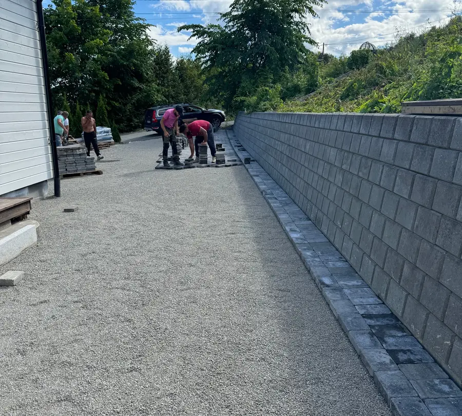 Lang støttemur i grå betongblokk langs oppkjørsel under opparbeiding