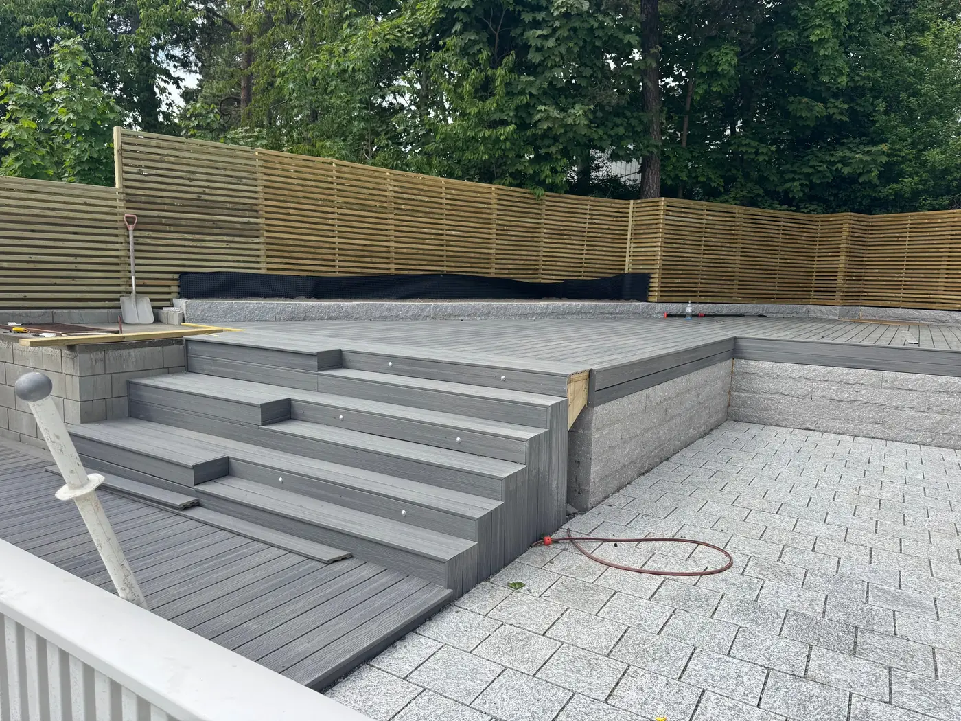 Hevet grå terrasse med trapp og betongblokkmur under